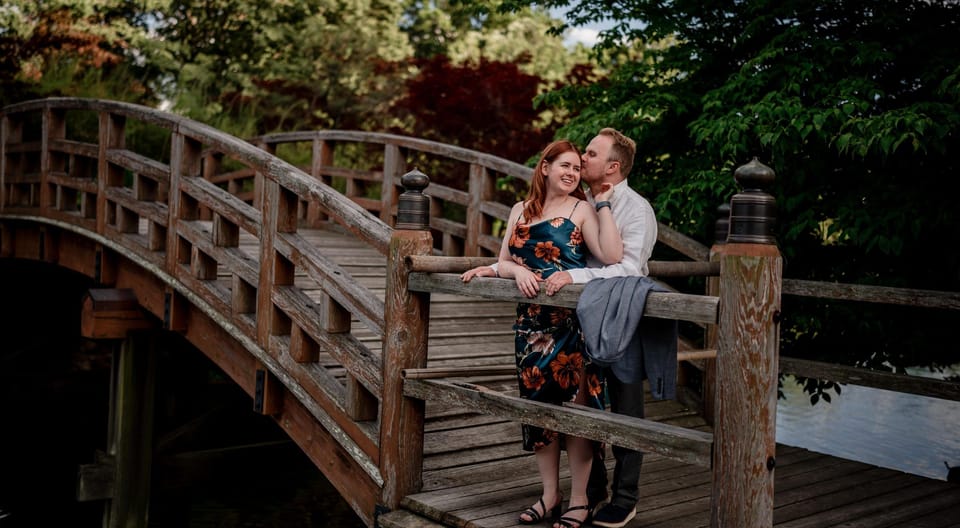 Steve and Katie standing together on a wooden footbridge over a pond